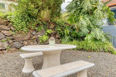 a stone table and bench with a cup of coffee on it at Casa do Pinheiro II, a Home in Madeira in São Vicente
