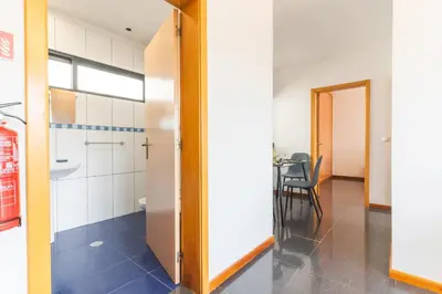 a hallway with a bathroom and a table with a chair at Porlamar Apartment by Atlantic Holiday in Calheta