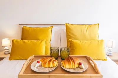 a tray with two croissants and two glasses on a bed at Porlamar Apartment by Atlantic Holiday in Calheta