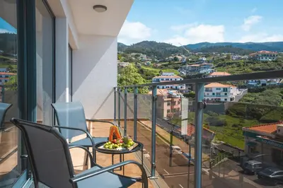 a balcony with chairs and a bowl of fruit on a table at Porlamar Apartment by Atlantic Holiday in Calheta