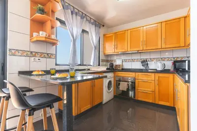 a kitchen with wooden cabinets and a black counter top at Porlamar Apartment by Atlantic Holiday in Calheta