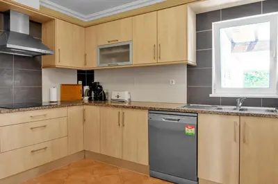 a kitchen with wooden cabinets and a dishwasher at L40 Villa & Pool- Vale da Telha, Aljezur in Aljezur