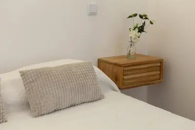 a vase of flowers sitting on a table next to a bed at A20 - Beco Luz Studio in Luz