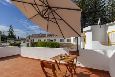 a patio with a table and chairs and an umbrella at A20 - Beco Luz Studio in Luz
