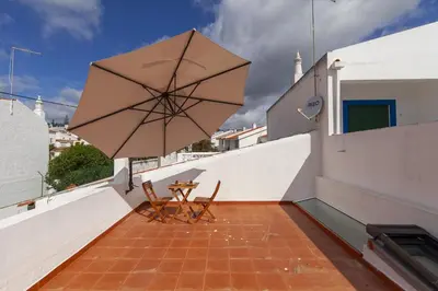 a patio with a table and an umbrella on a roof at A20 - Beco Luz Studio in Luz