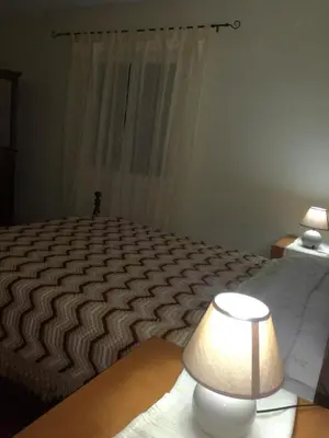 a bedroom with a bed and a lamp and a window at Casa do Pico in Câmara de Lobos