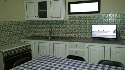 a kitchen with a table and a tv on a counter at Casa do Pico in Câmara de Lobos