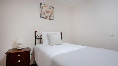a bedroom with a white bed and a nightstand with a teddy bear at Marroas Cottage in Ponta do Sol