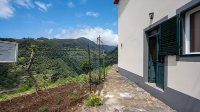 a building with a window and a view of a mountain at Marroas Cottage in Ponta do Sol