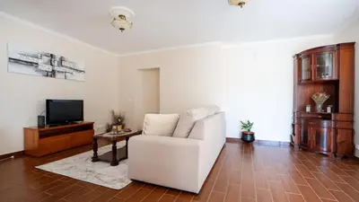 a living room with a white couch and a television at Marroas Cottage in Ponta do Sol