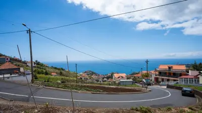 a winding road in a town with the ocean at Marroas Cottage in Ponta do Sol