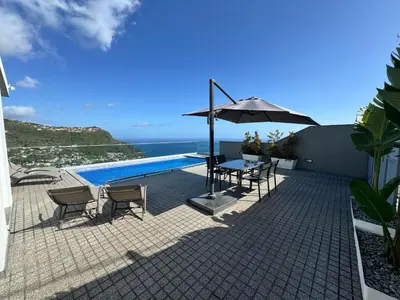 a patio with a table and chairs and an umbrella at Villa António in Arco da Calheta