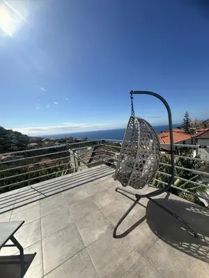 a patio with chairs and a table with a view of the ocean at Pearl Of The Sea in Ponta do Sol