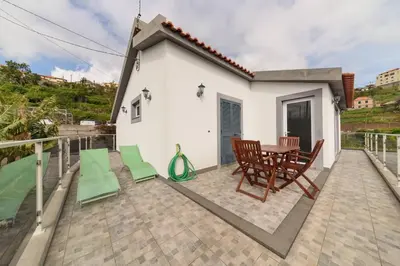 a patio with a table and chairs and a house at Vivenda Carlota Sea View by Mth in Ribeira Brava