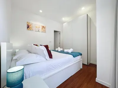 a white bedroom with a bed and a blue stool at CityZen Funchal by Atlantic Holiday in Funchal