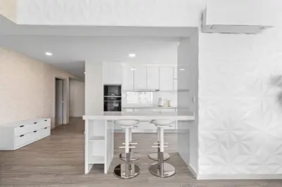 a white kitchen with a white counter and stools at Atlantic View by An Island Apart in Funchal