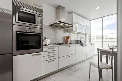 a kitchen with white appliances and a table with a chair at SeaSide Serenity in Funchal