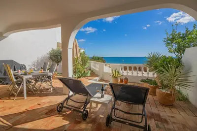 a patio with chairs and a table and the ocean at Apartamento Casa do Mar Praia da Luz in Luz