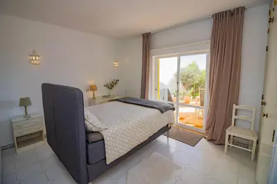 a bedroom with a bed with a chair and a window at Apartamento Casa do Mar Praia da Luz in Luz