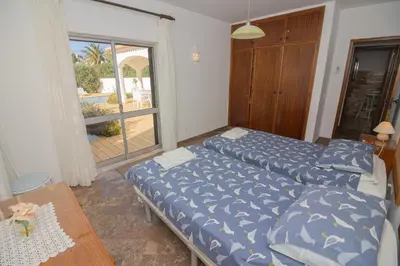 a bedroom with two beds and a table and a window at Casa dos Sonhos Praia da Luz in Luz