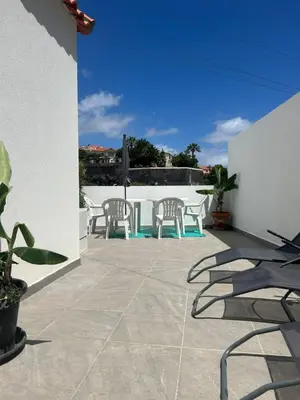 a patio with chairs and tables on a white wall at Casa Bamboo central Funchal Villa in Funchal