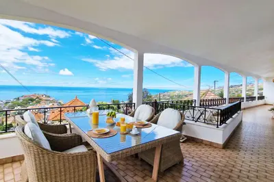a dining room with a table and chairs on a balcony at Villa Branca in Ponta do Sol