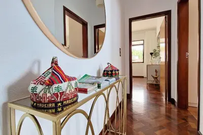 a hallway with a table with books and a mirror at Villa Branca in Ponta do Sol