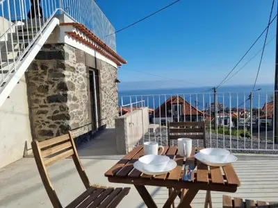 a wooden table with two glasses and a bottle of wine at Social Lodge Galinho House - Sea View - Calheta in Estreito da Calheta