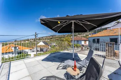 a kitchen with white cabinets and a table and a window at Social Lodge Galinho House - Sea View - Calheta in Estreito da Calheta