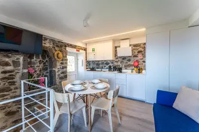 a bedroom with a bed and a stone wall at Social Lodge Galinho House - Sea View - Calheta in Estreito da Calheta