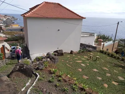 a balcony with two chairs and a table and a view at Vila Ladeira dos Zimbreiros - 3 bedroom, Jacuzzi, gym, AC, Pool with optional heated water in Paul do Mar