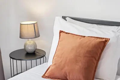a bed with a pillow and a lamp on a table at Locally by Homie in Funchal