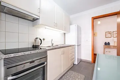 a white kitchen with a sink and a stove at Locally by Homie in Funchal