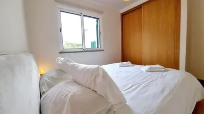 a white bed in a room with a window at Pestana Green View in Caniço