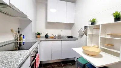 a kitchen with white cabinets and a wooden bowl on a counter at Pestana Green View in Caniço