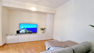 a living room with a flat screen tv on a white wall at Pestana Green View in Caniço