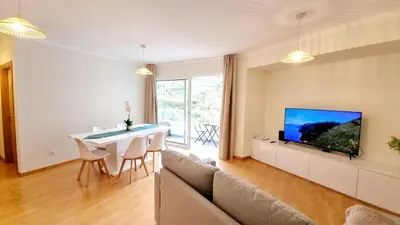 a living room with a couch and a table and a tv at Pestana Green View in Caniço