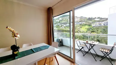 a dining room with a table and a large window at Pestana Green View in Caniço