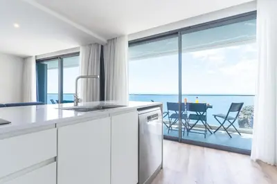 a white kitchen with a view of the ocean at Mar Apartment by Atlantic Holiday in Câmara de Lobos