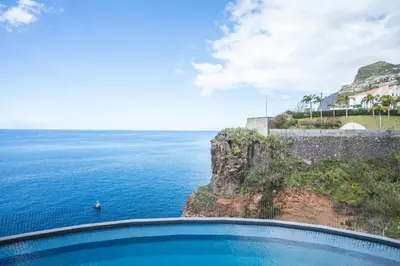 a swimming pool in front of the ocean at Mar Apartment by Atlantic Holiday in Câmara de Lobos