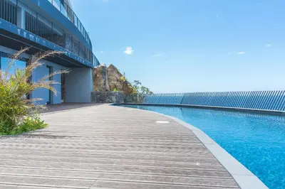a wooden walkway next to a building with a swimming pool at Mar Apartment by Atlantic Holiday in Câmara de Lobos
