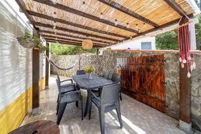 a patio with a table and chairs and a wooden pergola at Casa do Sol in Bordeira