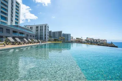 a large swimming pool with chairs and the ocean at Babi by the Sea by Atlantic Holiday in Funchal