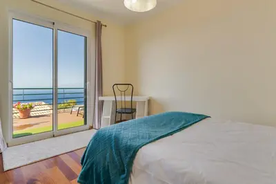 a bedroom with a bed and a large window at Calheta- Family home in Estreito da Calheta