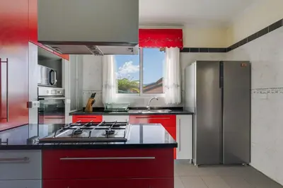 a kitchen with red cabinets and a stainless steel refrigerator at Calheta- Family home in Estreito da Calheta