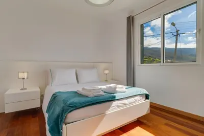 a white bedroom with a bed and a window at Calheta- Family home in Estreito da Calheta
