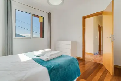 a white bedroom with a bed with towels on it at Calheta- Family home in Estreito da Calheta