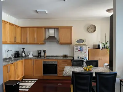 a kitchen with wooden cabinets and a table with chairs at Surf Nest in Machico