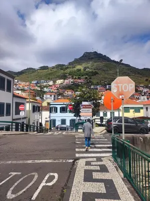 a man walking down a street with a stop sign at Surf Nest in Machico