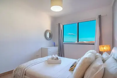 a white bedroom with a bed and a window at Apartment 7 on Paul do Mar Beach in Paul do Mar